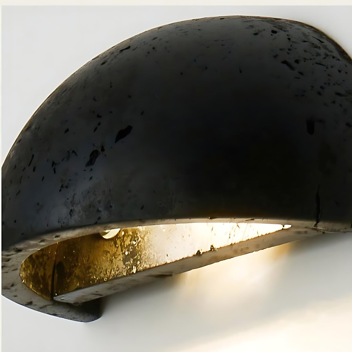 Close view of the black travertine Mira LED wall sconce with its gold lined inside