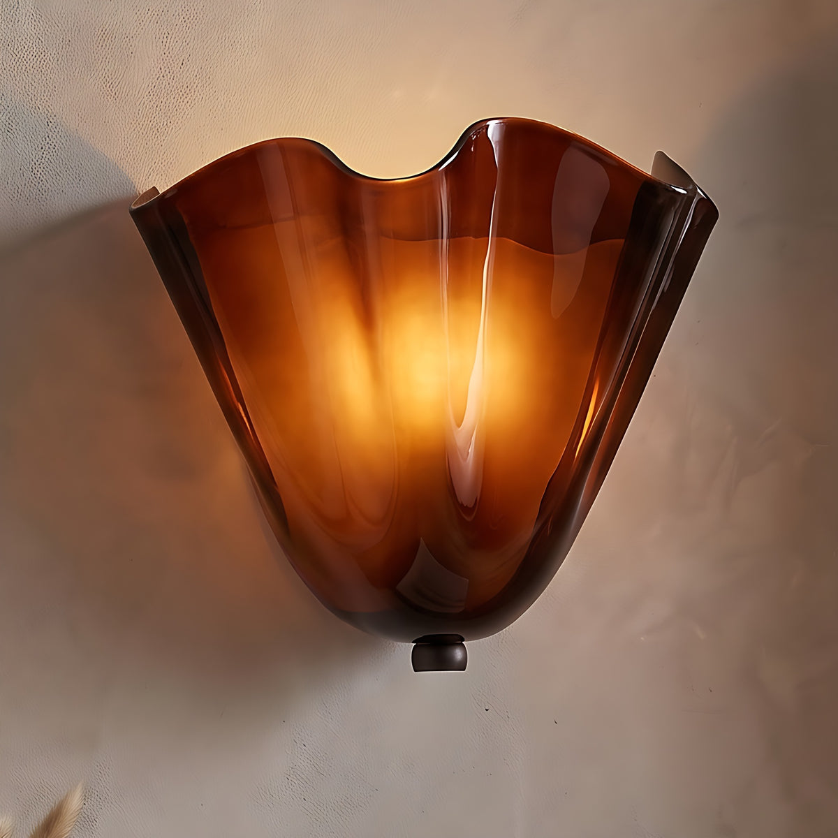 Moa wall sconce, brown ruffled glass shell, lit on a warm beige plaster wall
