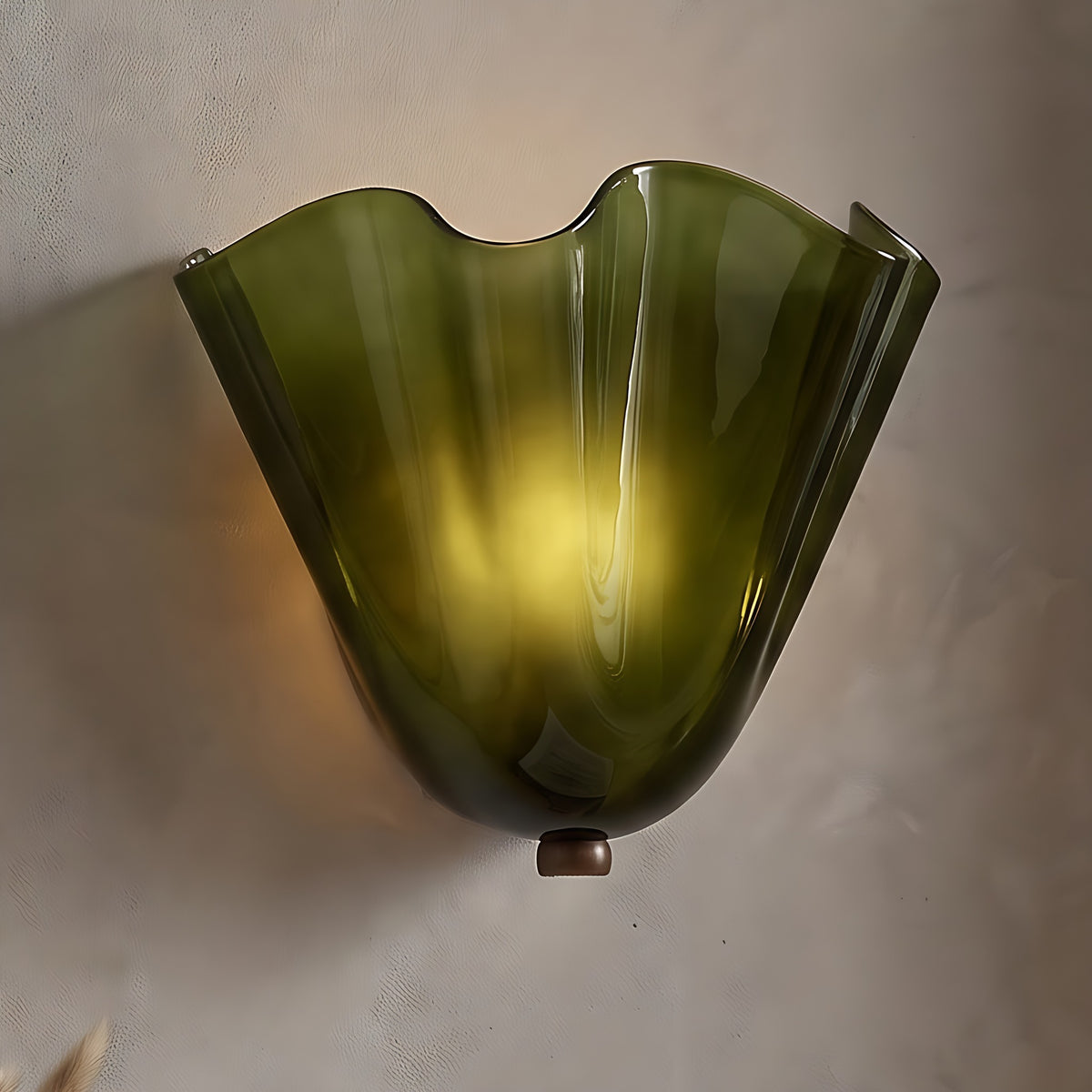 Moa wall sconce, green ruffled glass shell, lit on a warm beige plaster wall