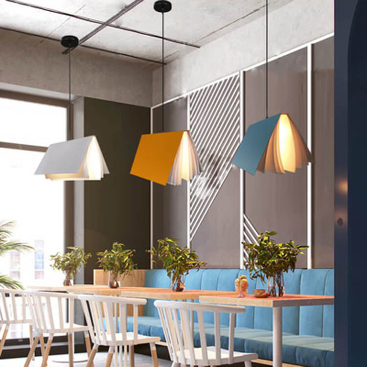 White, yellow and blue book pendants over a cafe style dining area with plants