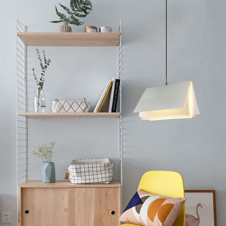 White book pendant hanging beside open shelving in a bright room with a yellow chair