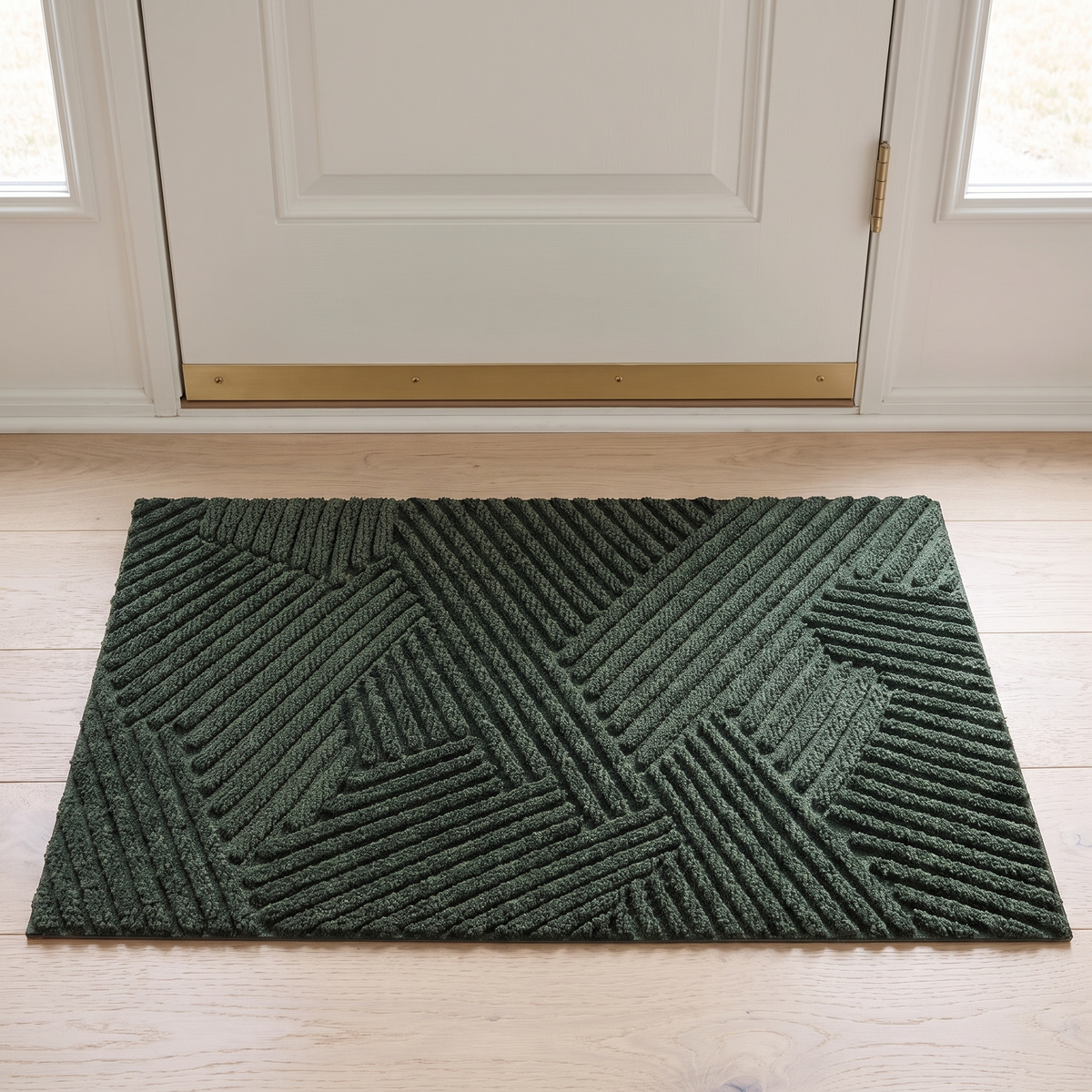 Green non slip door mat inside a white front door on an oak floor