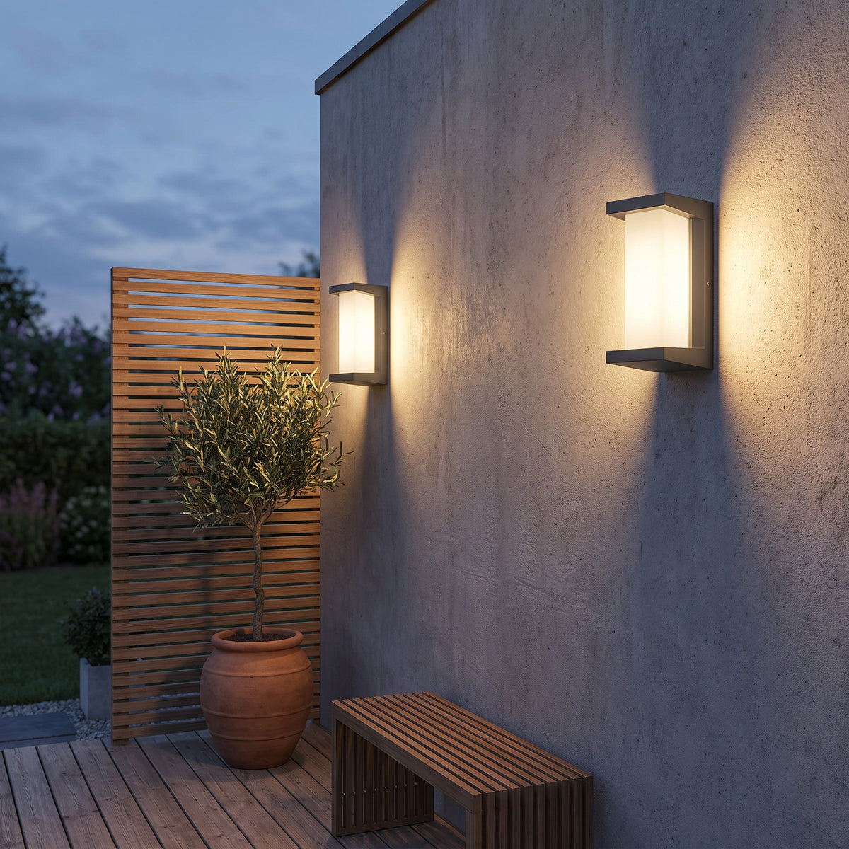 Two outdoor motion sensor wall lights on a concrete wall beside a slatted screen at dusk