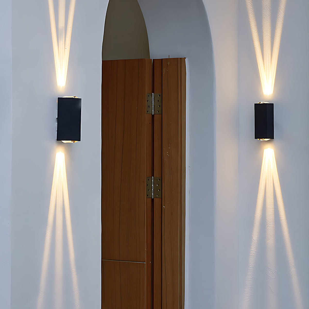 Two outdoor wall sconces beaming light up and down beside a wooden door