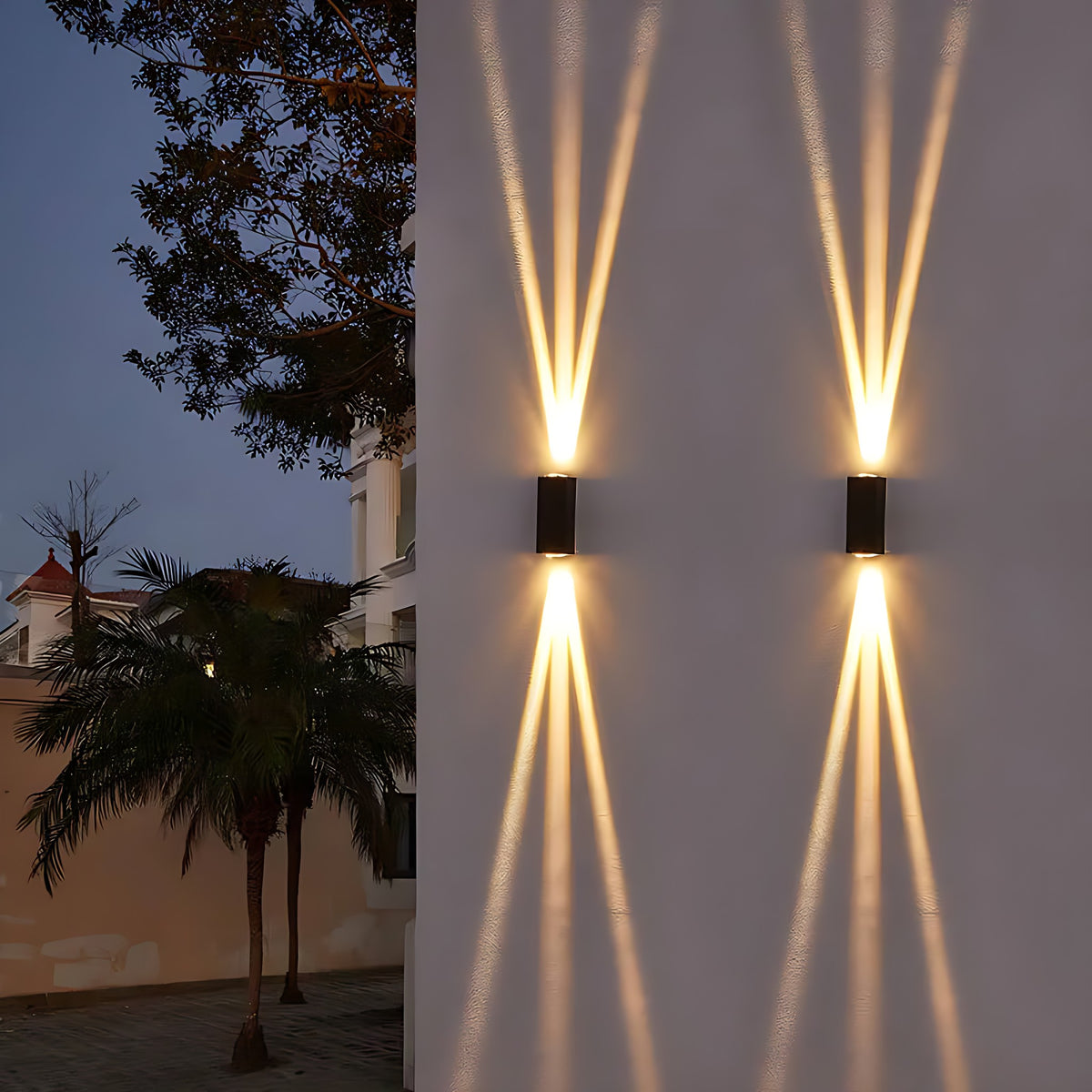 Two outdoor wall sconces casting narrow and wide beams on a facade at dusk