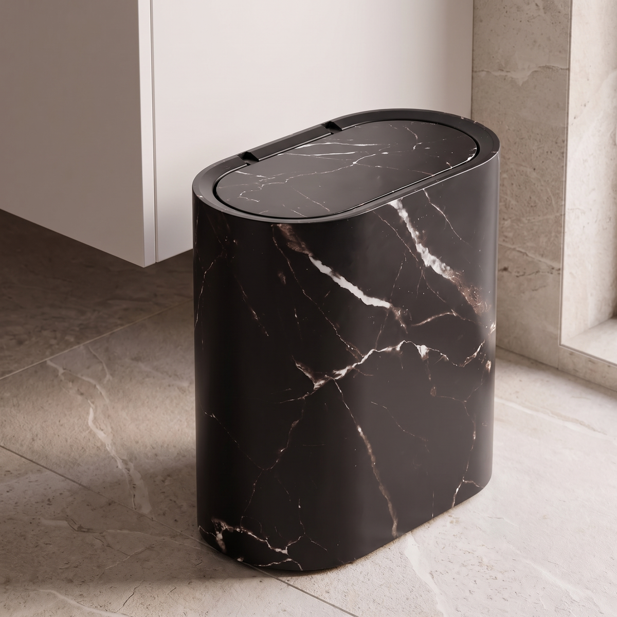 Oval waste bin in black marble beside a bathroom vanity