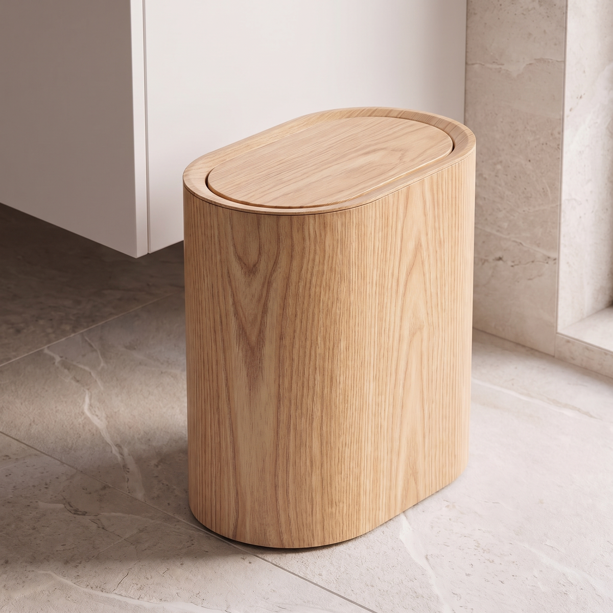 Oval waste bin in light wood grain beside a bathroom vanity