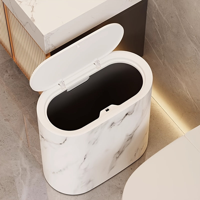 Cream marble oval waste bin with the lid flipped open on a bathroom floor