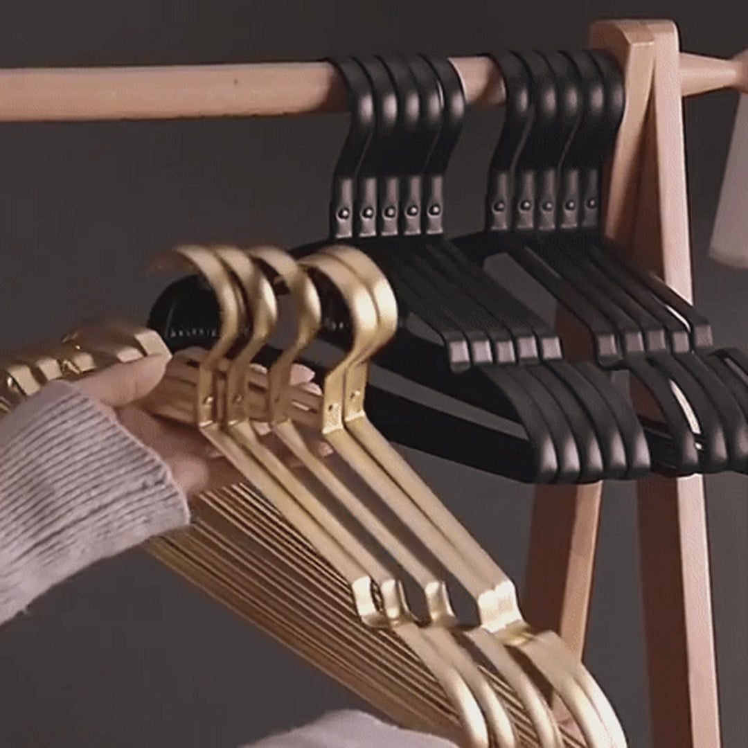 Hanging tops and dresses on gold and black aluminum hangers on a wooden rack