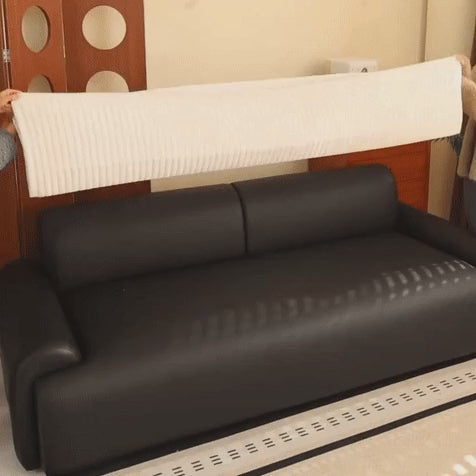 Quilted couch cover lifted, laid along a sofa seat and smoothed flat