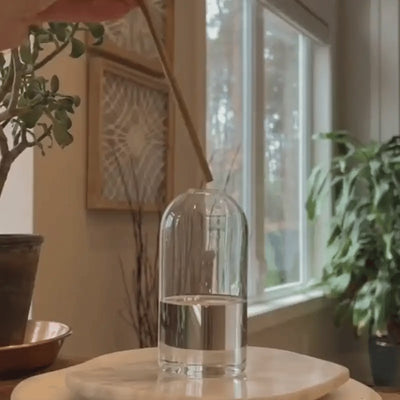 Skive glass oil candles being lit in their glass vessel by a window