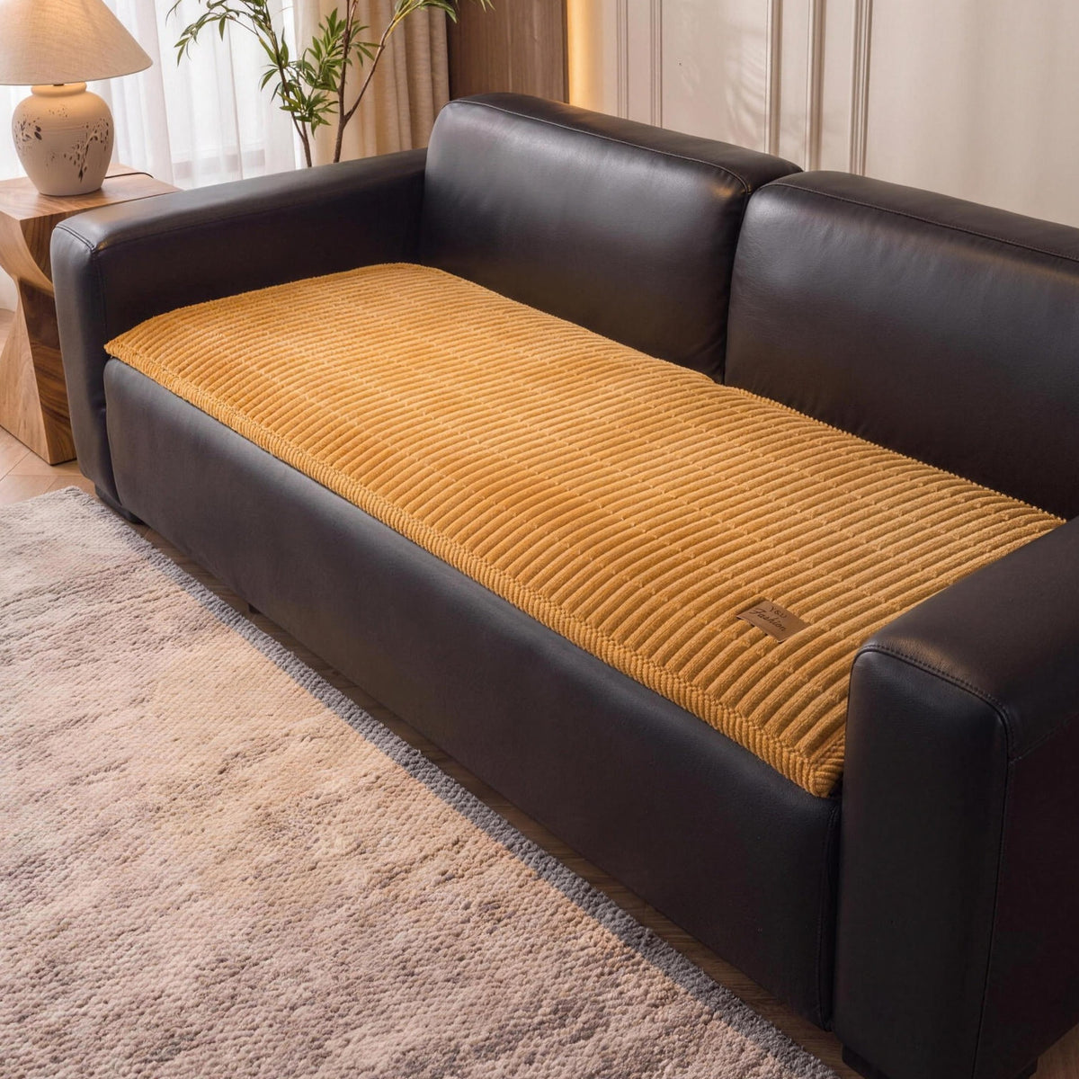 Quilted couch cover in Amber on the seat of a black leather sofa
