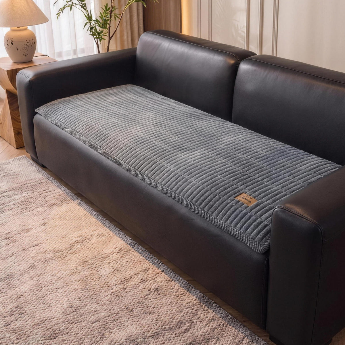 Quilted couch cover in Slate Gray on the seat of a black leather sofa