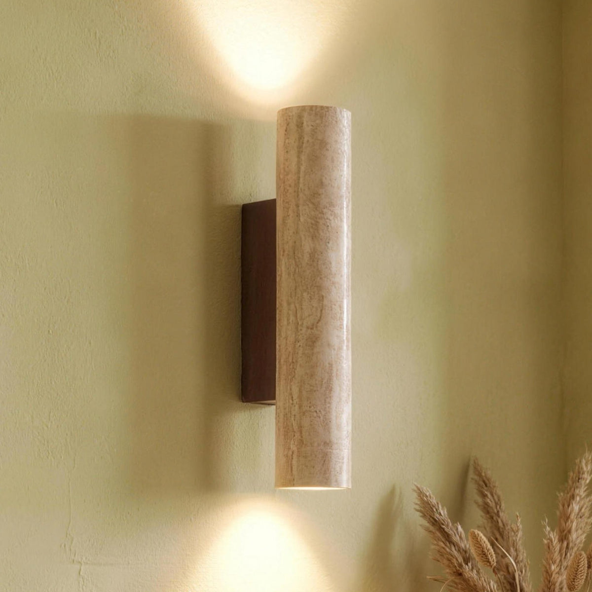 Rakel travertine wall sconce lit up and down on a warm plaster wall
