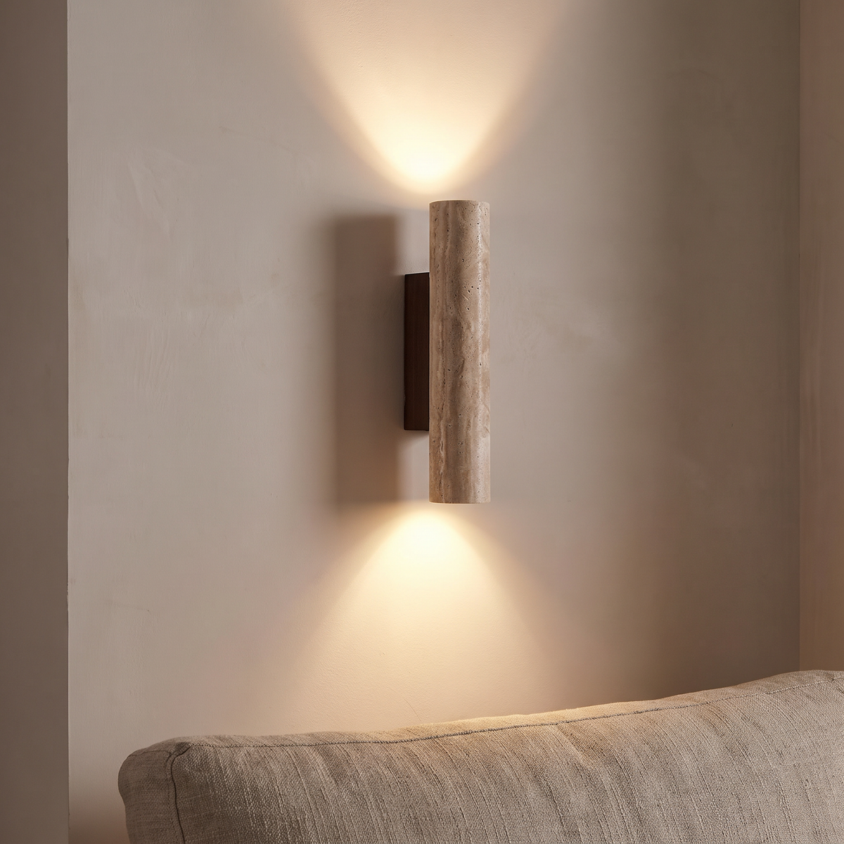 Rakel wall sconce washing a limewashed wall above and below at the end of a linen sofa