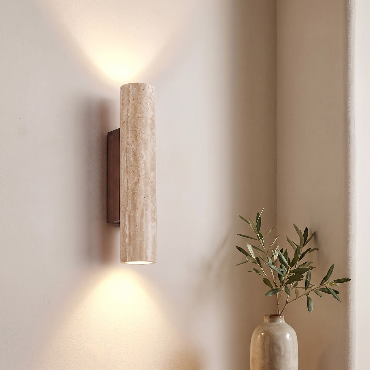 Close view of the Rakel sconce travertine cylinder and wood plate on a bedroom wall