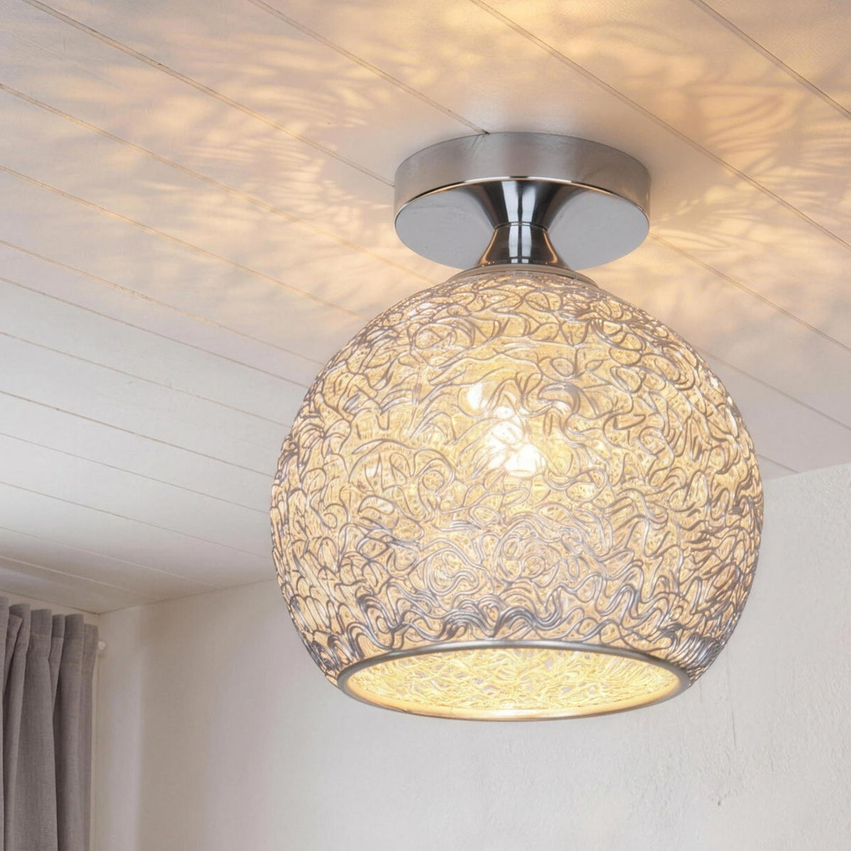 Silver Saara wire dome ceiling light lit on a white ceiling