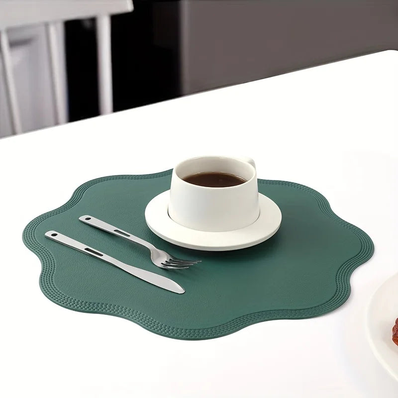 Green scalloped placemat with a coffee cup, saucer, fork and knife on a white table