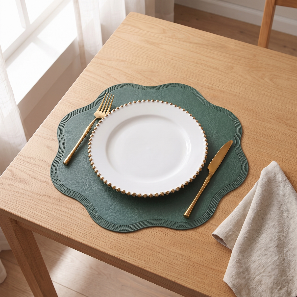 Green scalloped round placemat with a white plate, gold fork and knife on an oak table