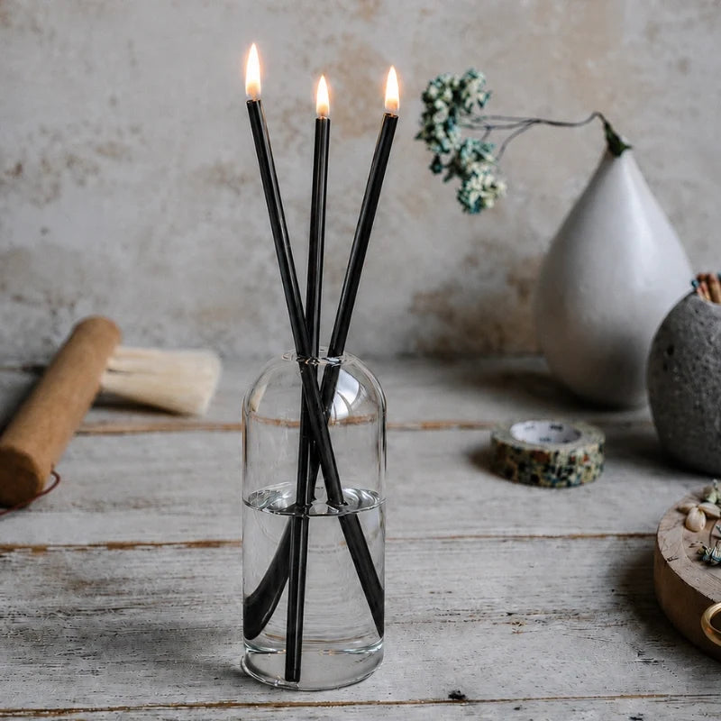 Skive black oil candles on a pale wood table