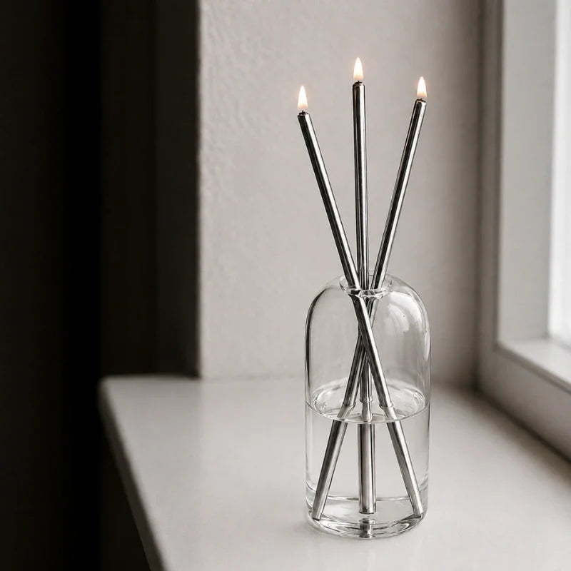 Skive silver oil candles lit on a white windowsill