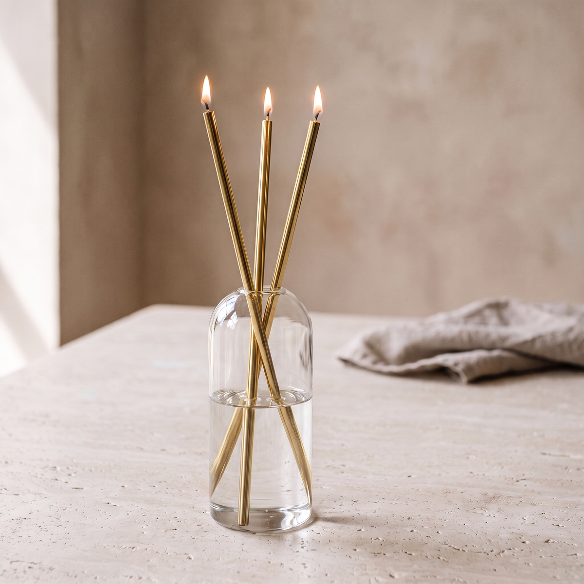 Skive oil candles with gold stems lit on a limestone table