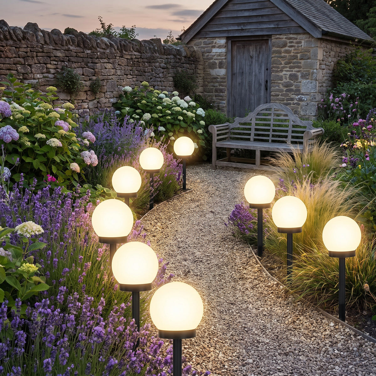 A row of solar globe stake lights with warm light along a gravel garden path