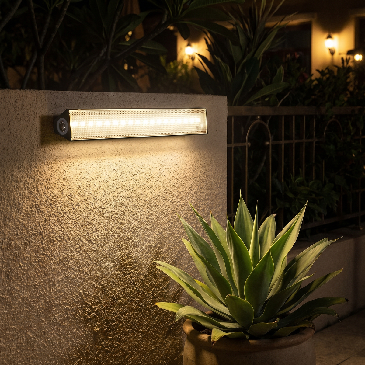 Solar wall light bar on a stucco garden wall at night