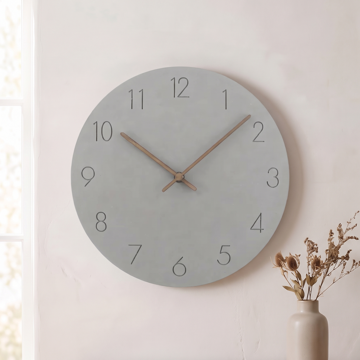 Sten wall clock with a gray dial on a plaster wall