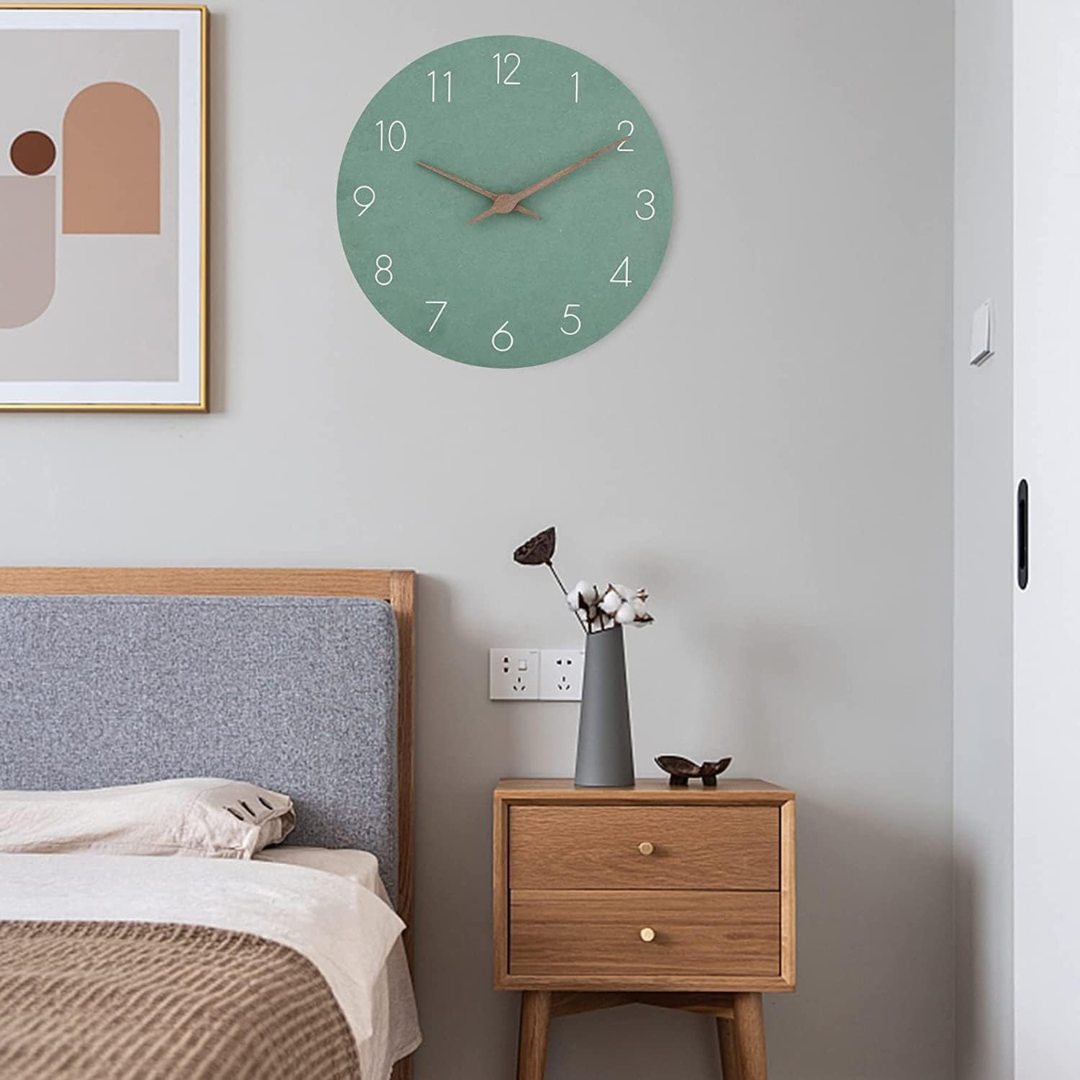 Sage green wall clock above a nightstand beside a bed