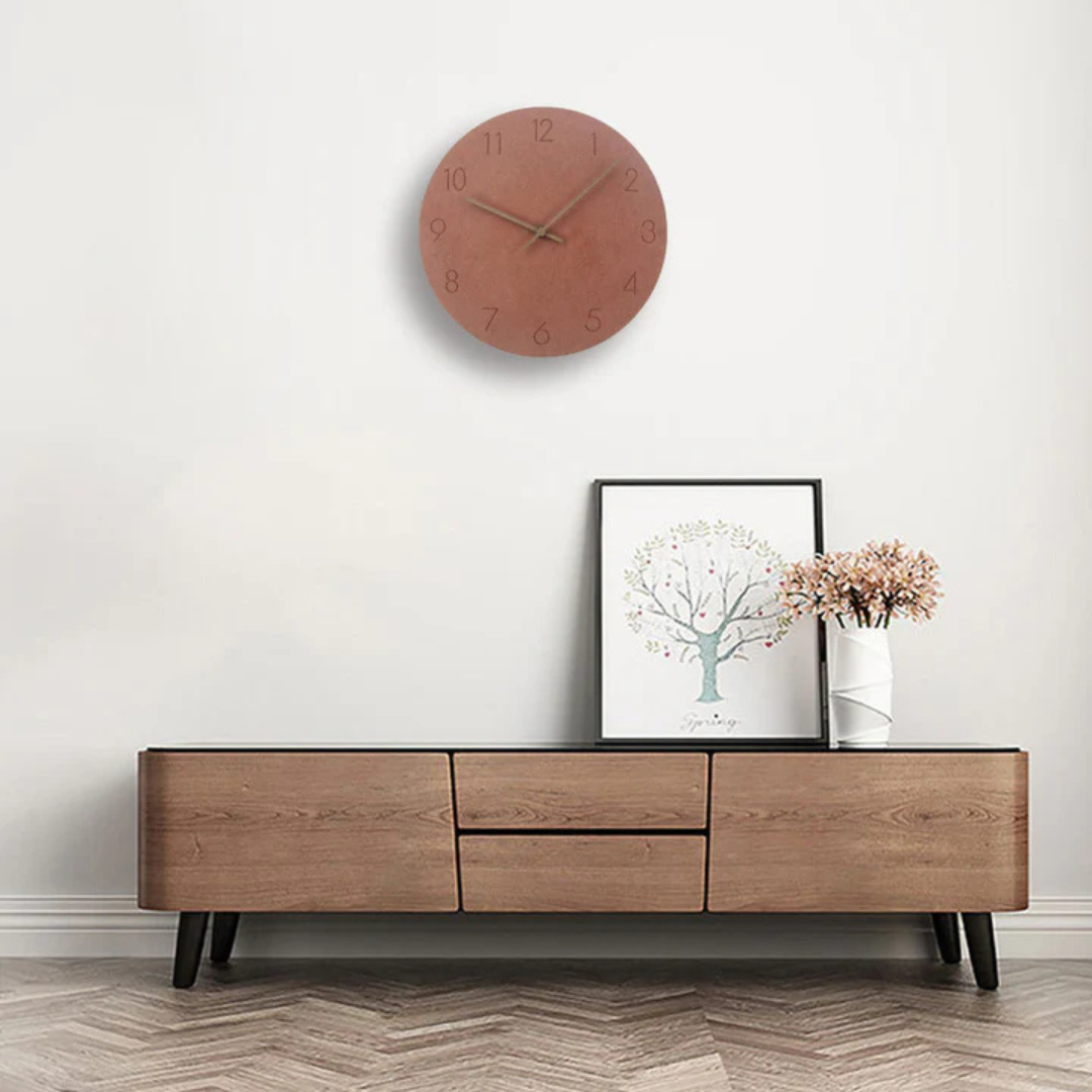 Terracotta wall clock hung above a walnut media console with a framed print