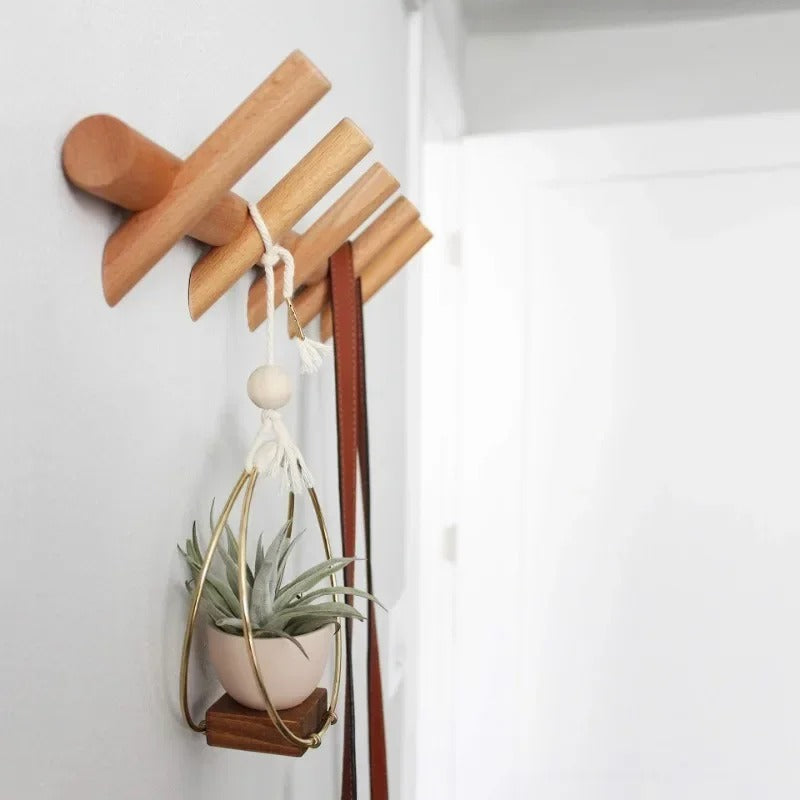 Stord oak peg rack with a hanging plant and a leather strap on its pegs