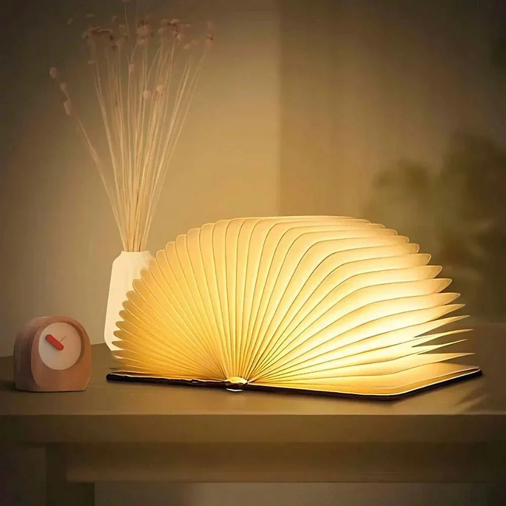 Sula book lamp opened flat into a glowing fan on a dark wood sideboard