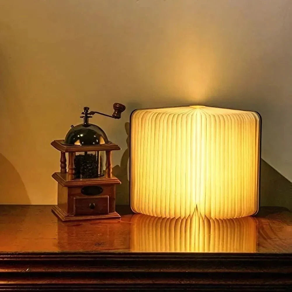 Sula book lamp standing half open and glowing on a sideboard beside a coffee grinder