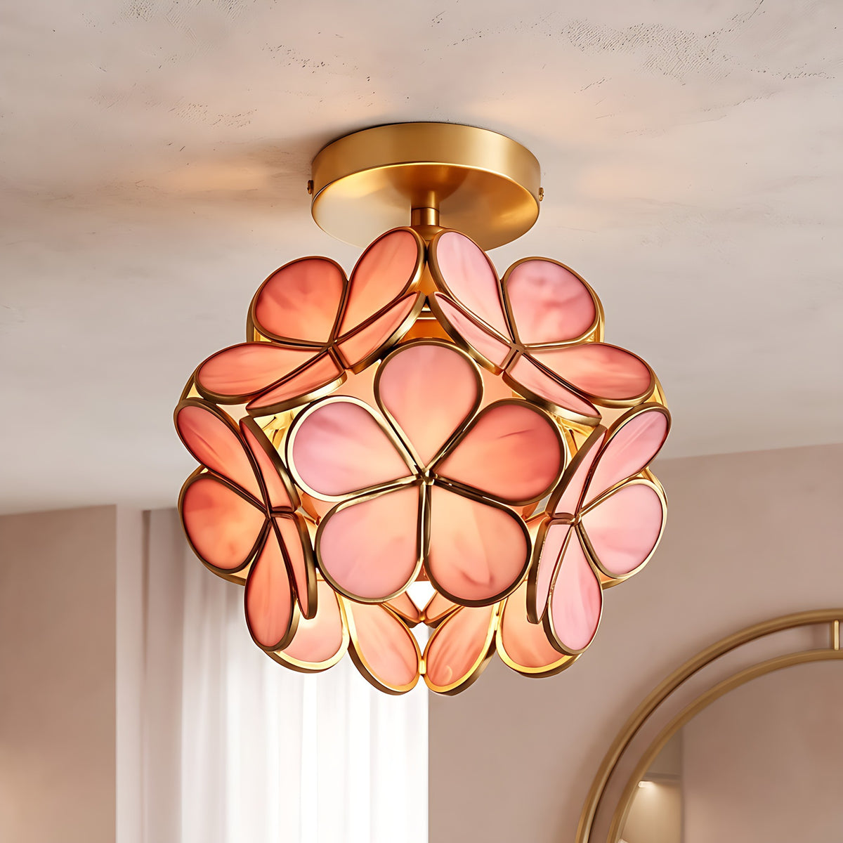 Pink Sunna glass petal ceiling light lit on a plaster ceiling