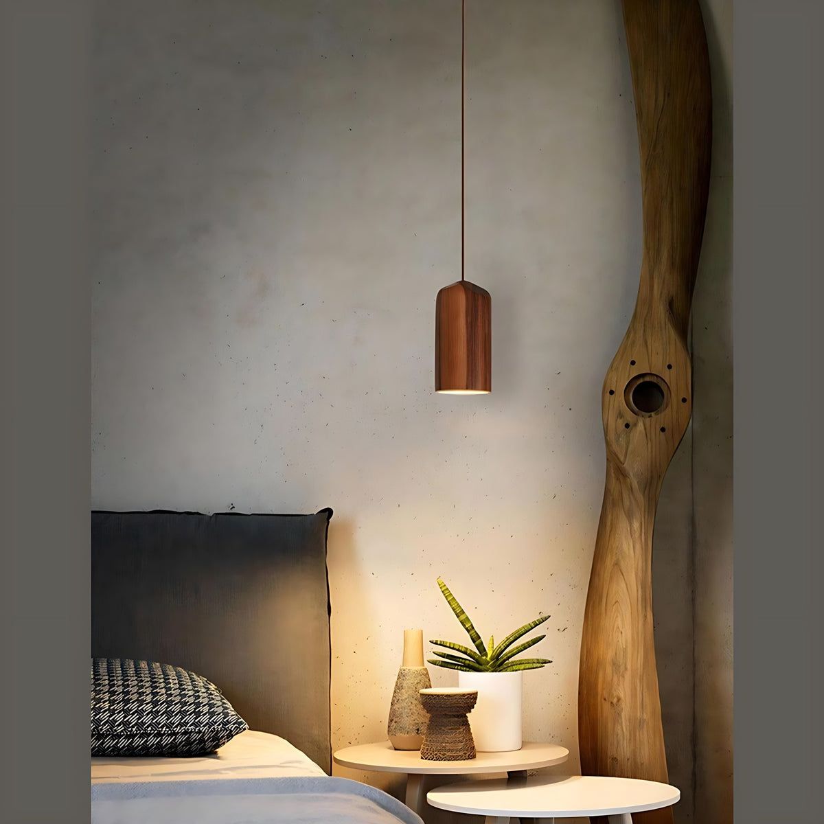 Svea wood pendant light in walnut, lit beside a bedside table