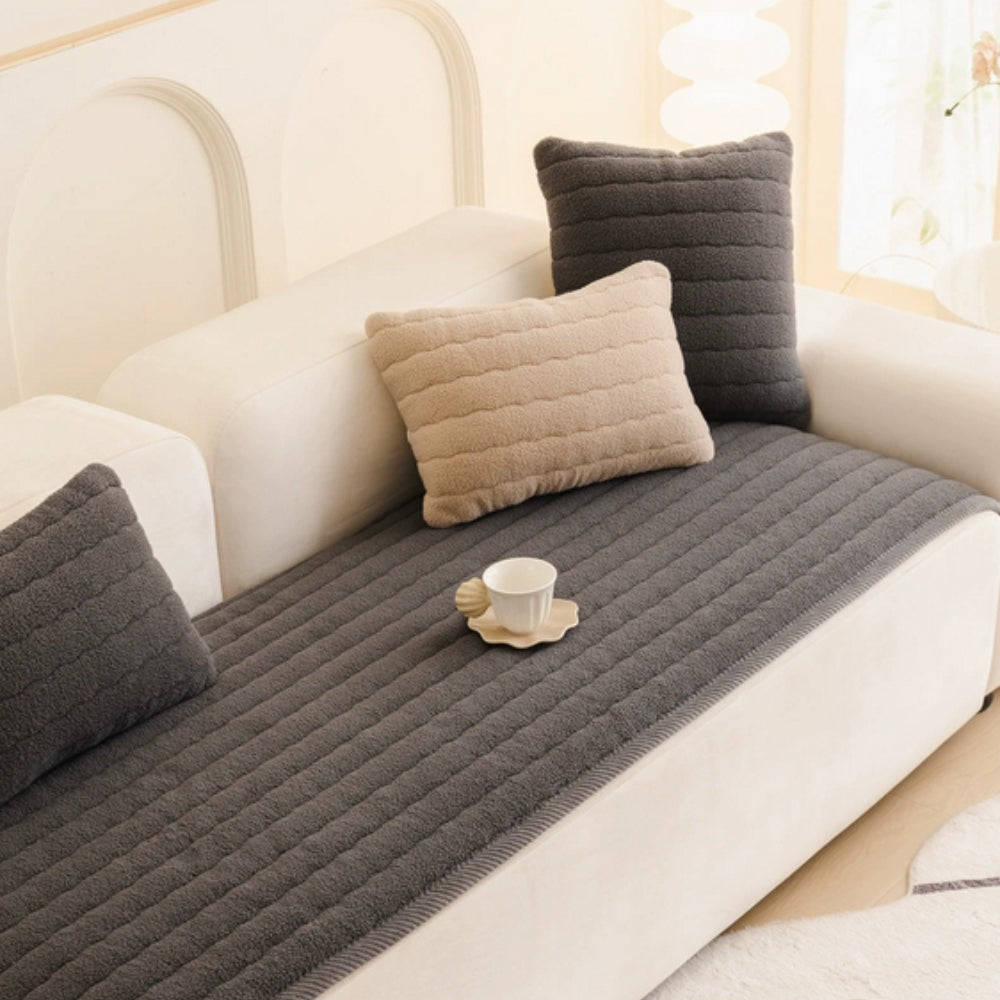 Charcoal quilted sofa cover on a white sofa with matching pillows