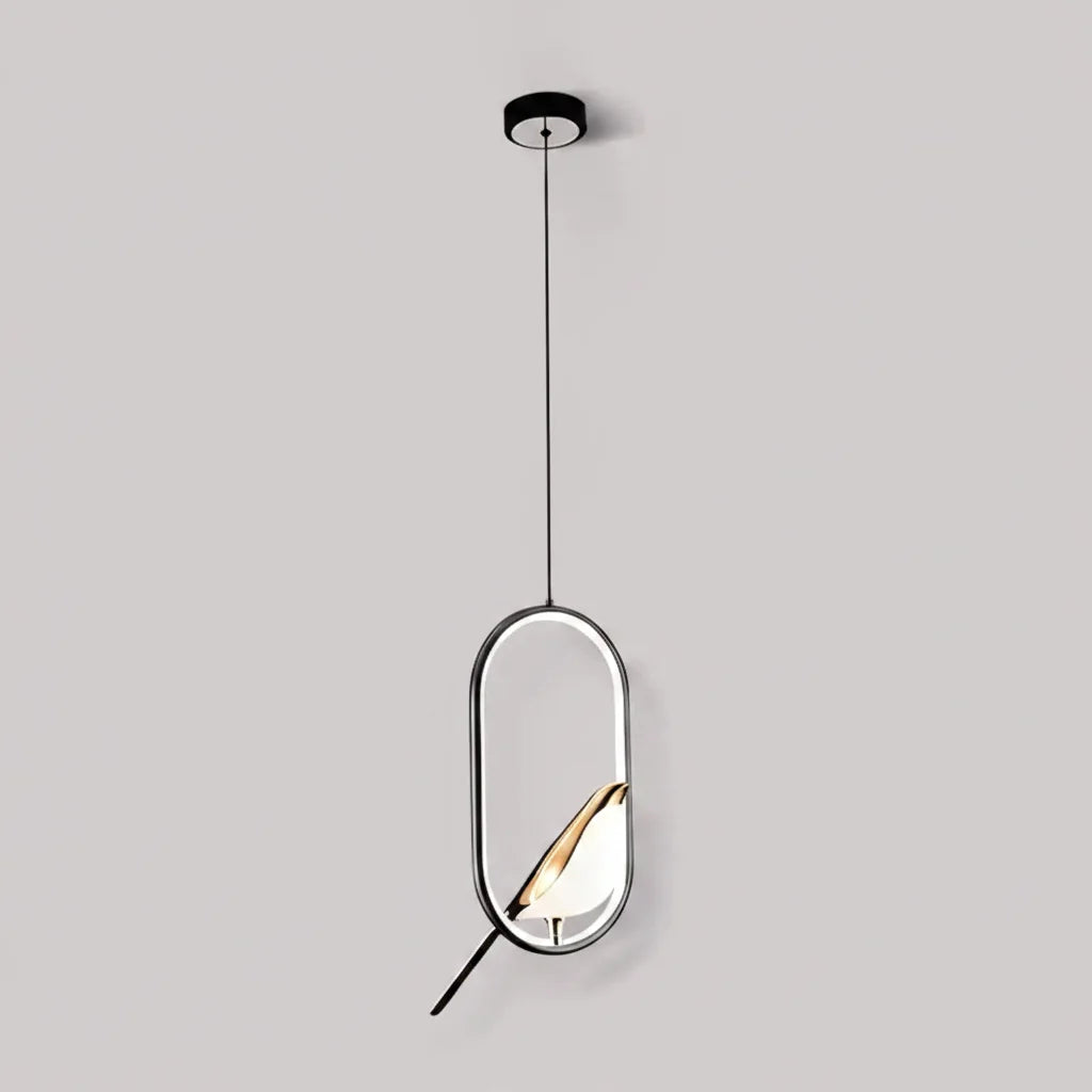 Black oval frame bird pendant with a gold accented bird against a pale gray wall