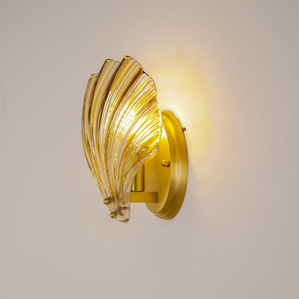 Side view of the Tyra shell sconce standing off its round gold plate