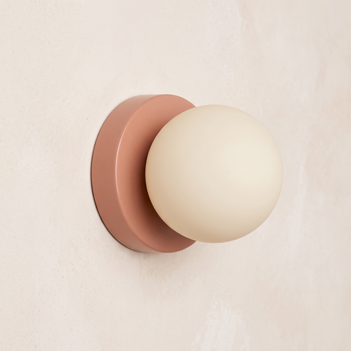 Close view of the Ulla wall sconce in Pink on a plaster wall