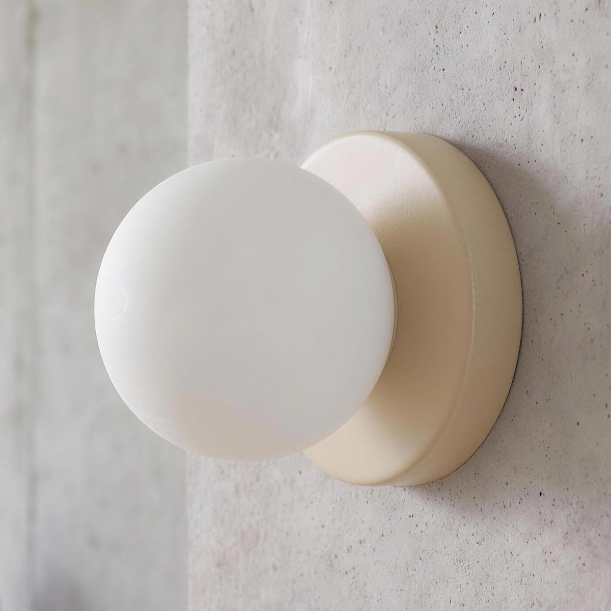 Ulla wall sconce in Beige against a concrete wall