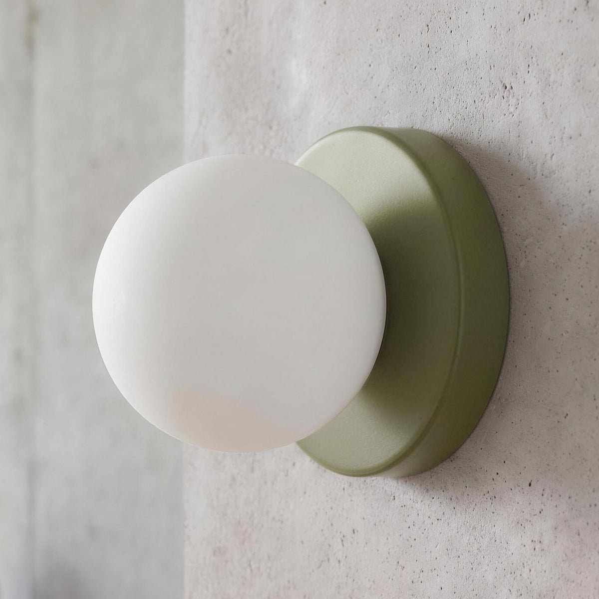 Ulla wall sconce in Green against a concrete wall
