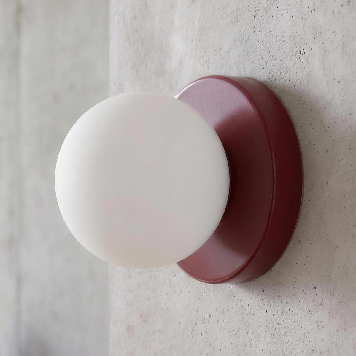 Ulla wall sconce in Red against a concrete wall