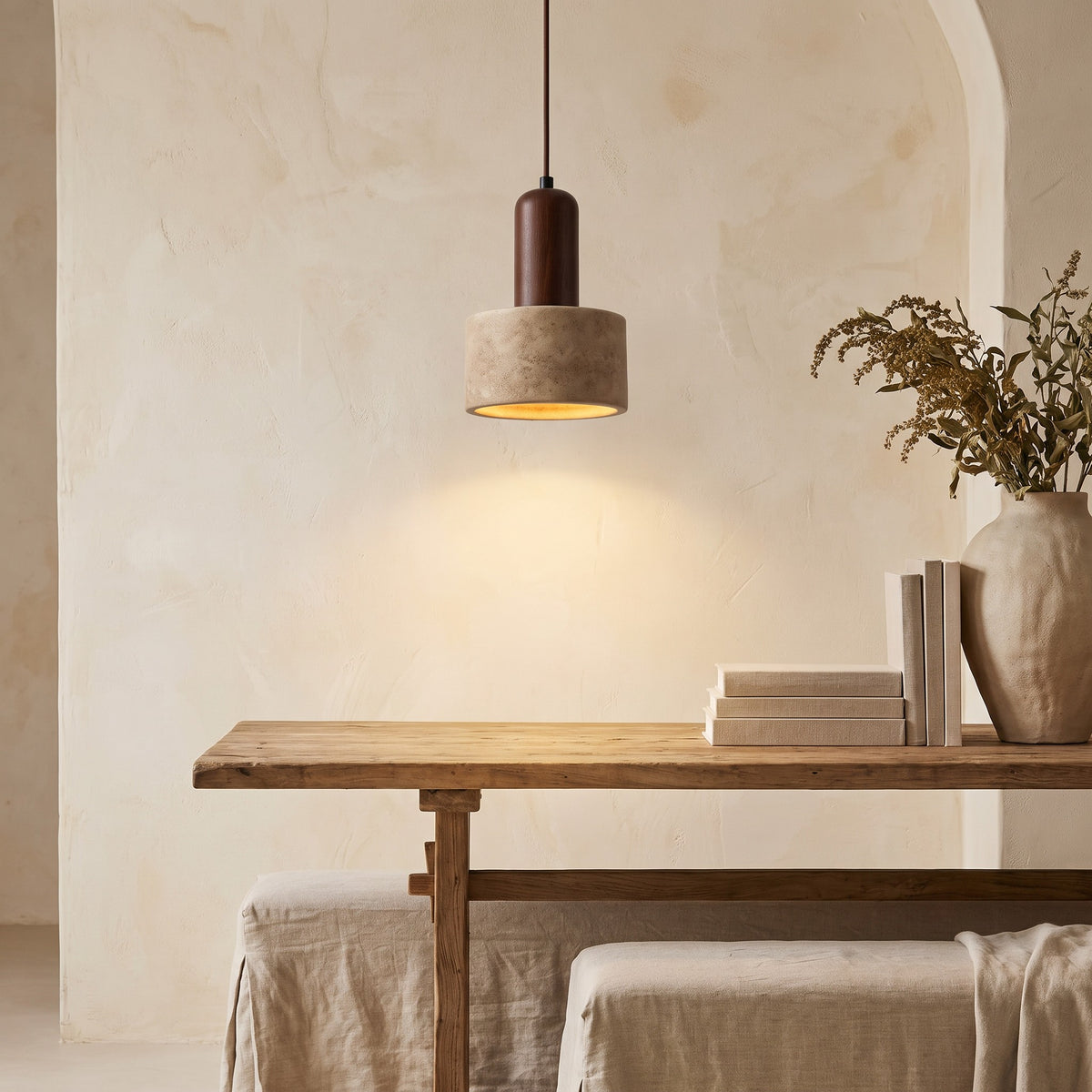 Vanja travertine pendant light lit over a wooden table