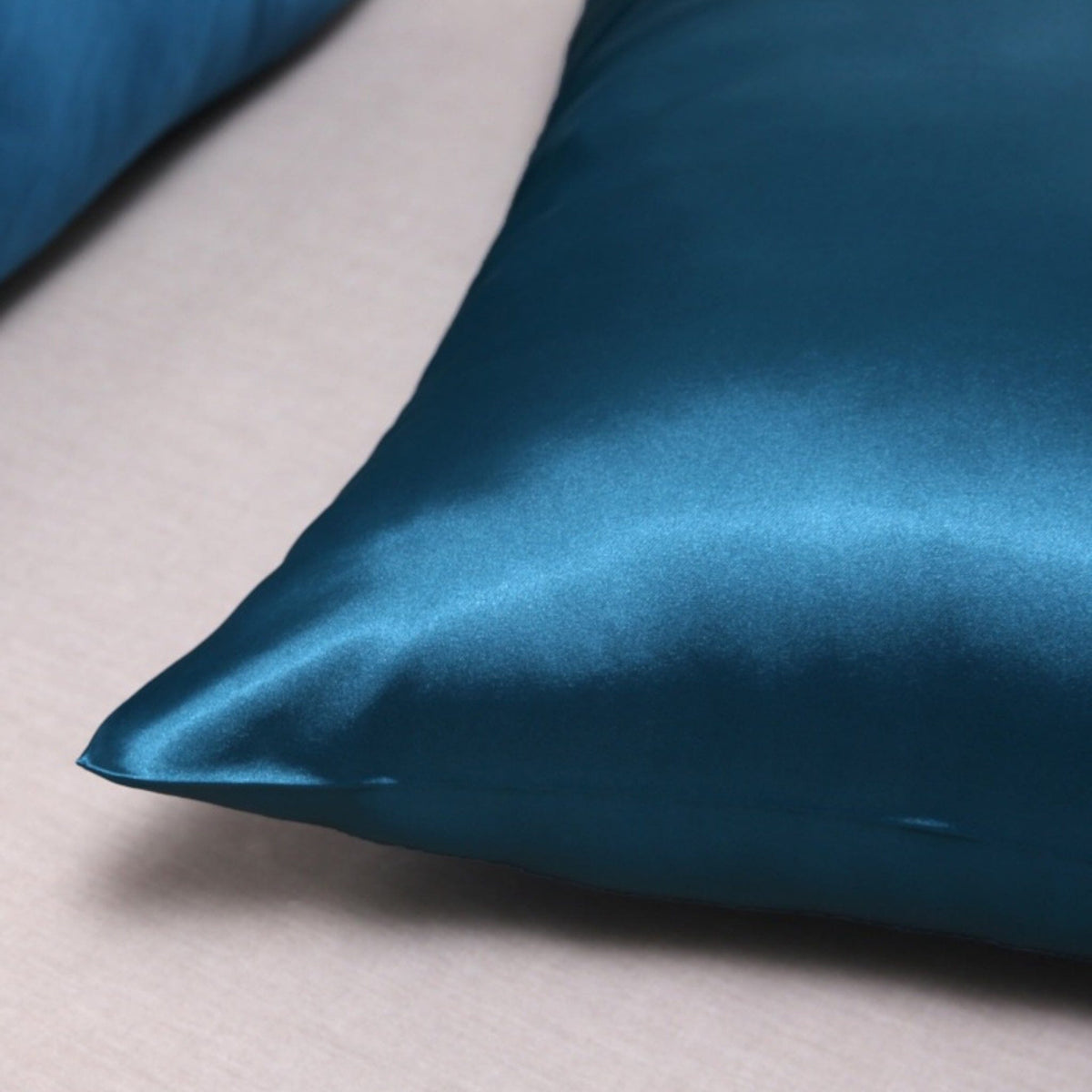 Corner of a peacock blue Vilde satin pillowcase