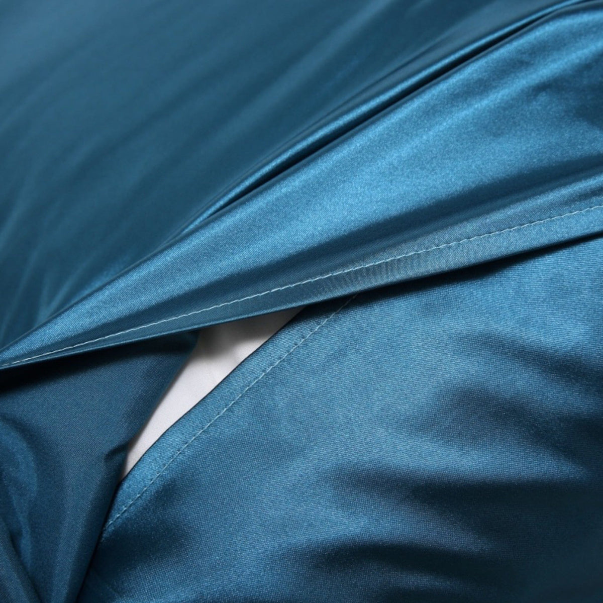Envelope flap opening of a peacock blue Vilde satin pillowcase