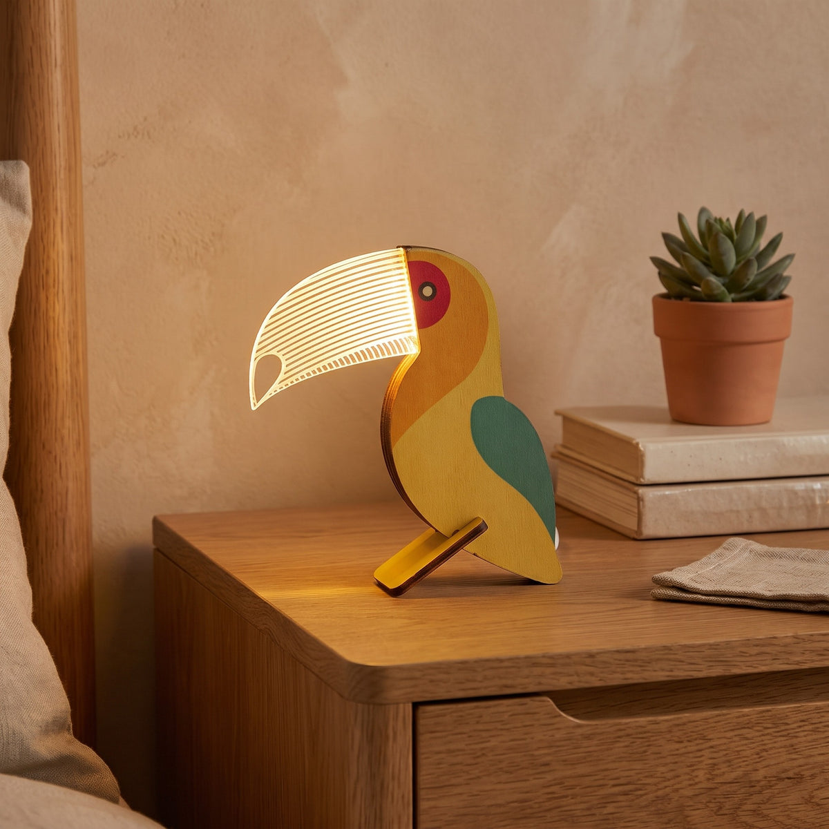 Vilma night light, toucan design, glowing on a bedside table