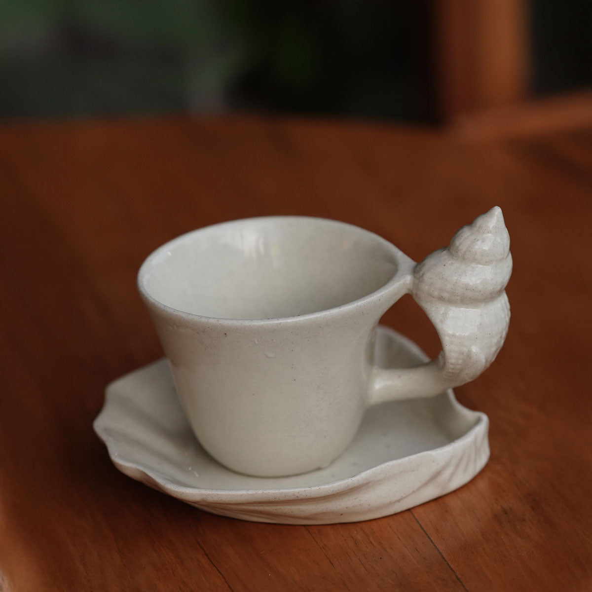 Cup and saucer on a wooden table showing the rippled shell saucer