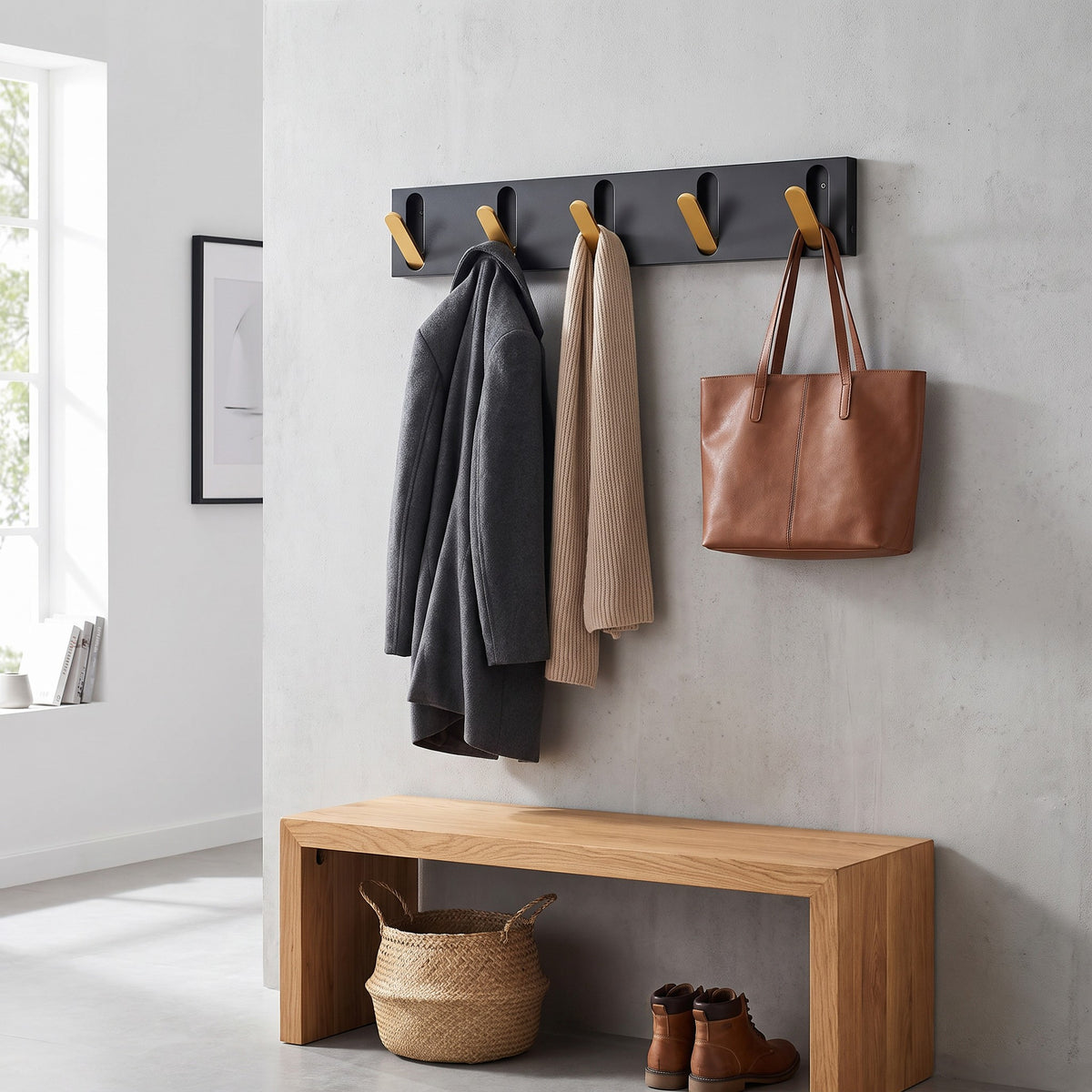 Gold flip out hooks holding coats, a scarf and a tote bag above a bench