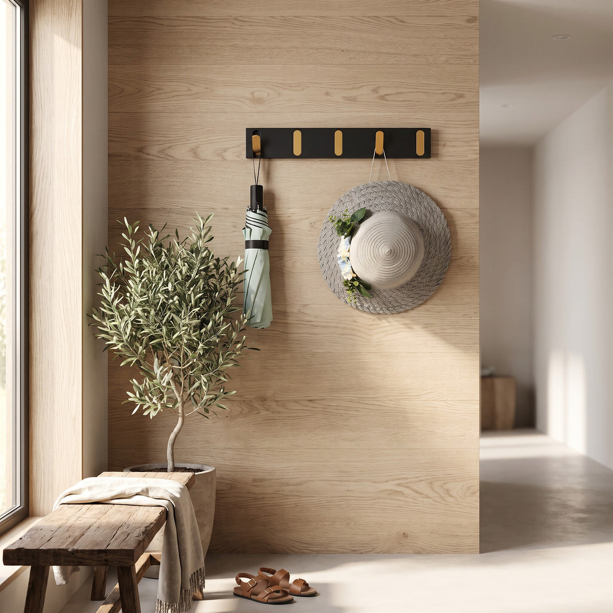 Wall hook rack with gold flip out hooks holding an umbrella and a hat in an entryway